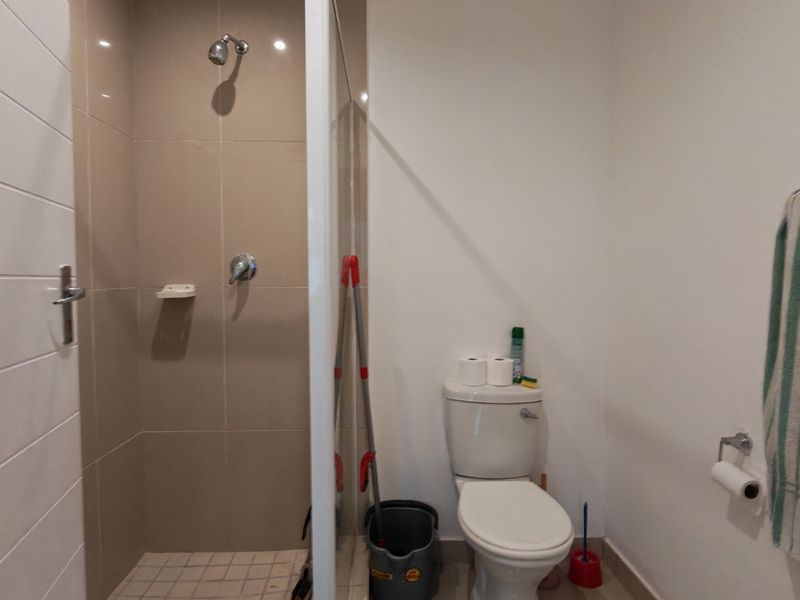 A functional bathroom featuring a tiled shower enclosure with a glass screen and a standard toilet.