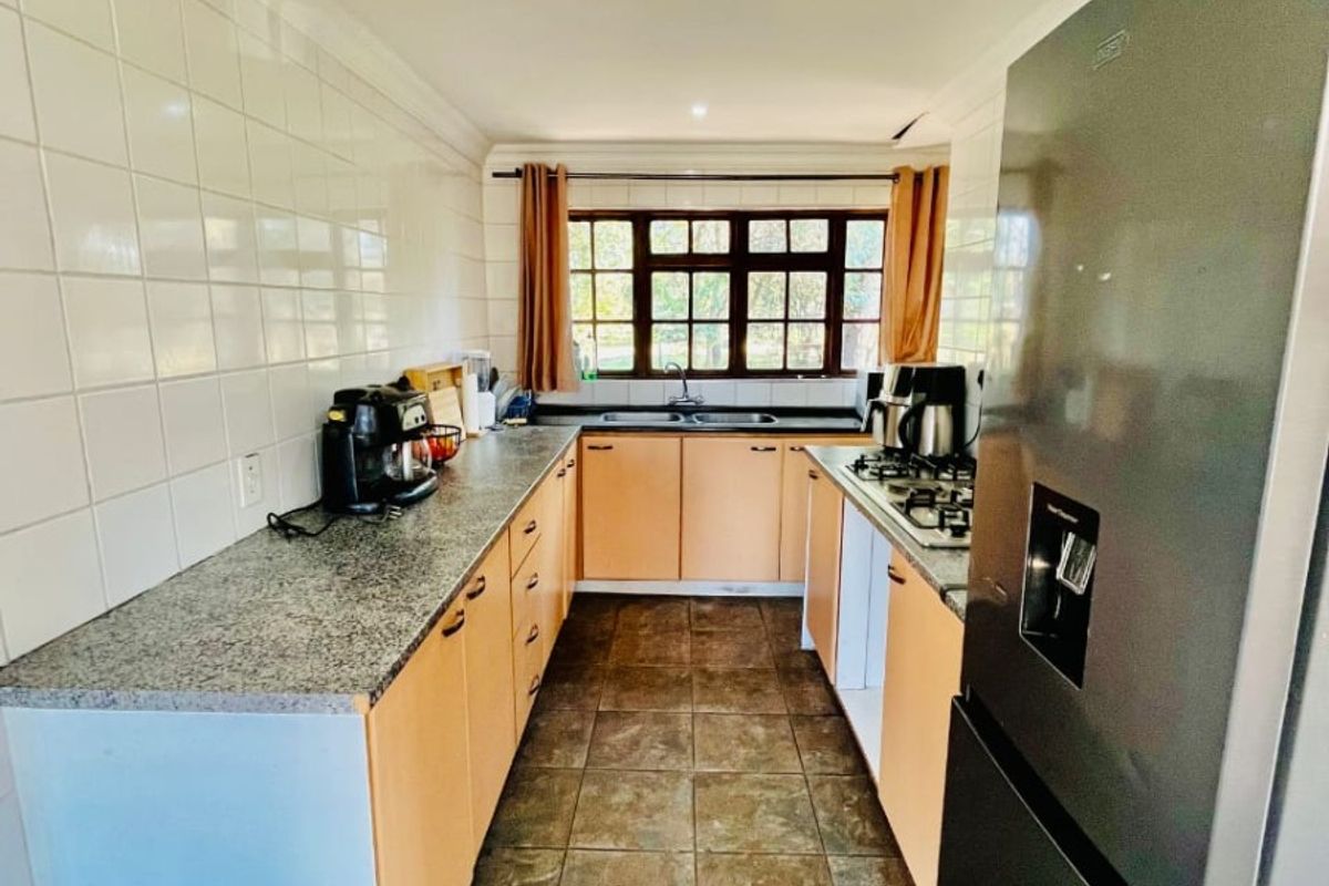 A functional galley-style kitchen featuring granite countertops, tiled backsplash, built-in cabinetry, and a gas hob, offering a practical layout for daily meal preparation.