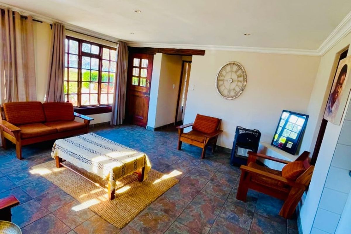 Spacious living room featuring natural slate-style floor tiles, recessed lighting, and large timber-framed windows allowing for ample natural light.