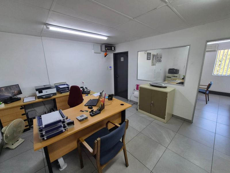 Functional office space featuring tiled flooring, a drop ceiling, and an internal glass partition providing visibility into the adjacent area.