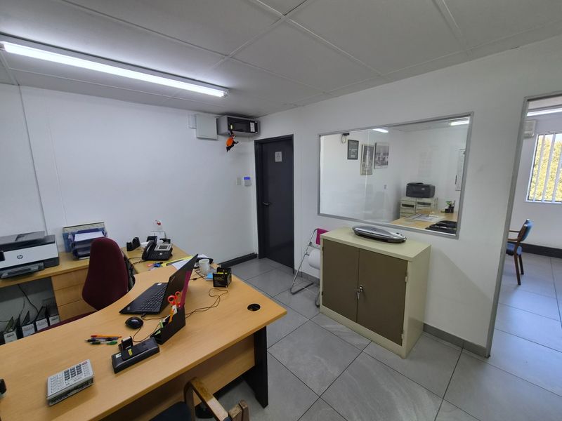 Functional office space featuring tiled flooring, a suspended ceiling, and an internal glass partition providing visibility into the adjacent room.