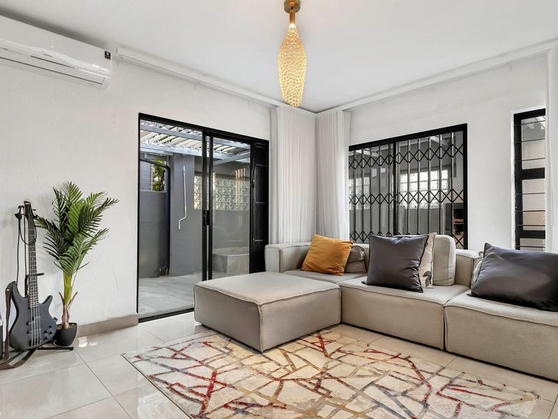 A bright and modern living room featuring tiled flooring, a split-system air conditioner, and large sliding glass doors leading to an outdoor area.