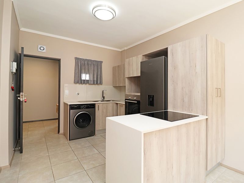 Modern kitchen featuring light wood-grain cabinetry, laminate countertops, integrated oven and cooktop, and tiled flooring in a clean, functional layout.