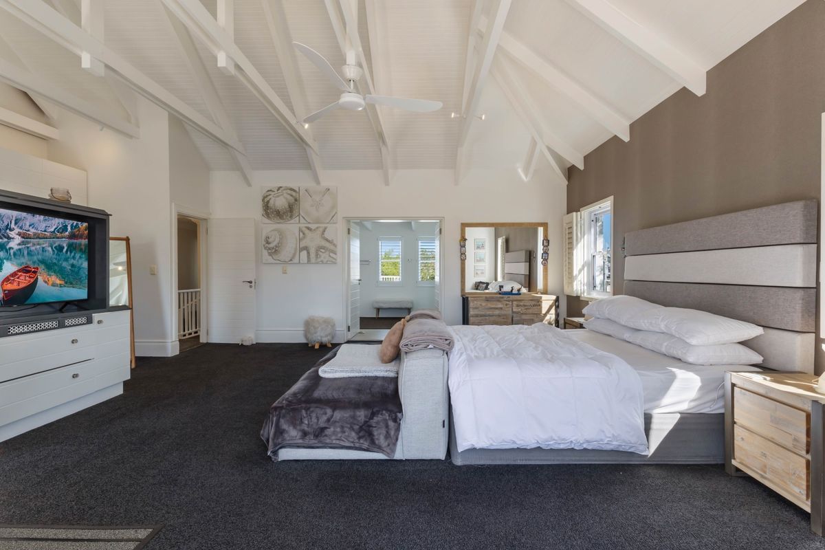 Spacious bedroom featuring a high vaulted ceiling with exposed rafters, ceiling fan, and neutral finishes, offering a bright and airy atmosphere.
