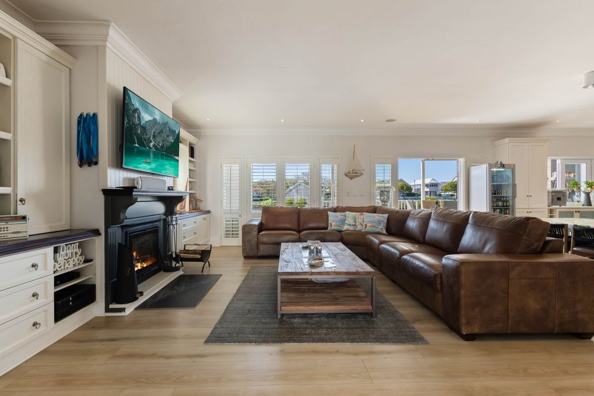 Spacious living room featuring a fireplace with built-in cabinetry, plantation shutters, and light-toned laminate flooring, creating a warm and inviting atmosphere.