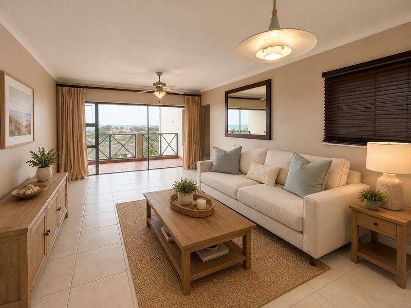 A bright and well-maintained living room featuring tiled floors, a ceiling fan, and large sliding glass doors that open onto a private balcony.