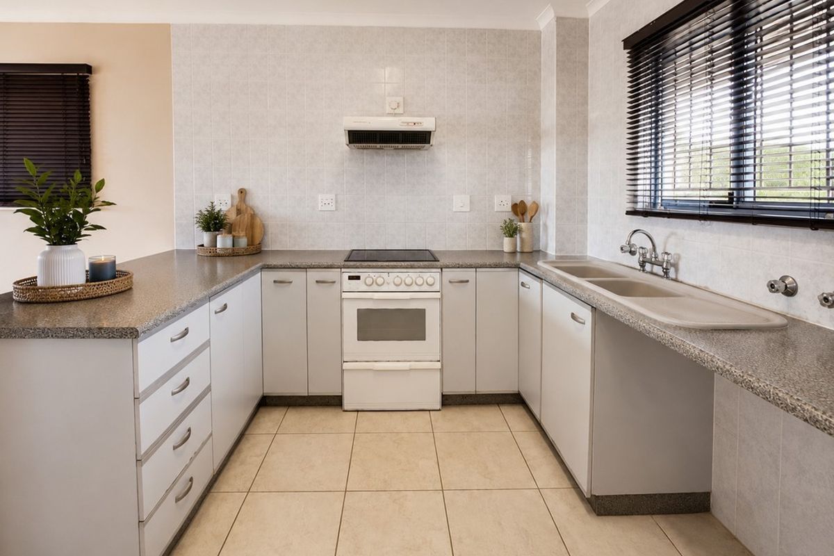 A functional U-shaped kitchen featuring light-toned cabinetry, granite-look laminate countertops, a freestanding stove with extractor, and a double basin sink.