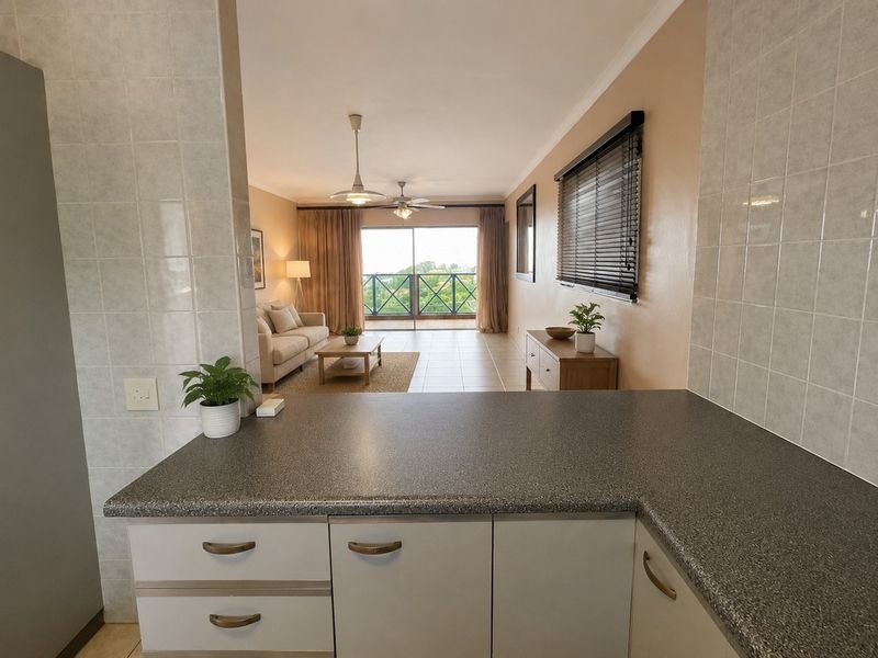 Open-plan kitchen and living area featuring tiled floors, built-in cabinetry, and sliding doors leading to a balcony with scenic views.