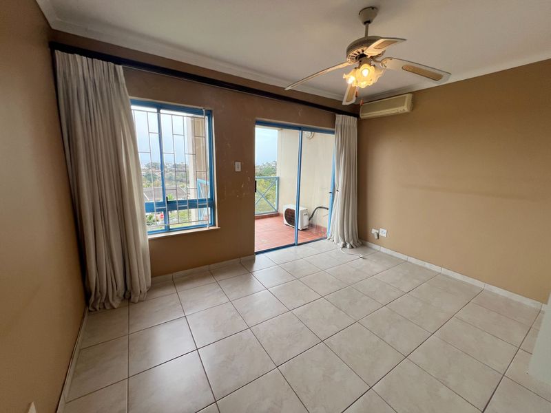An empty bedroom featuring tiled floors, a ceiling fan, split-system air conditioning, and direct access to a private balcony.