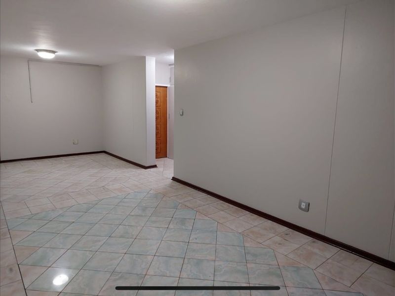An empty, open-plan living area featuring neutral walls, tiled flooring, and basic lighting fixtures, providing a blank canvas for interior design.