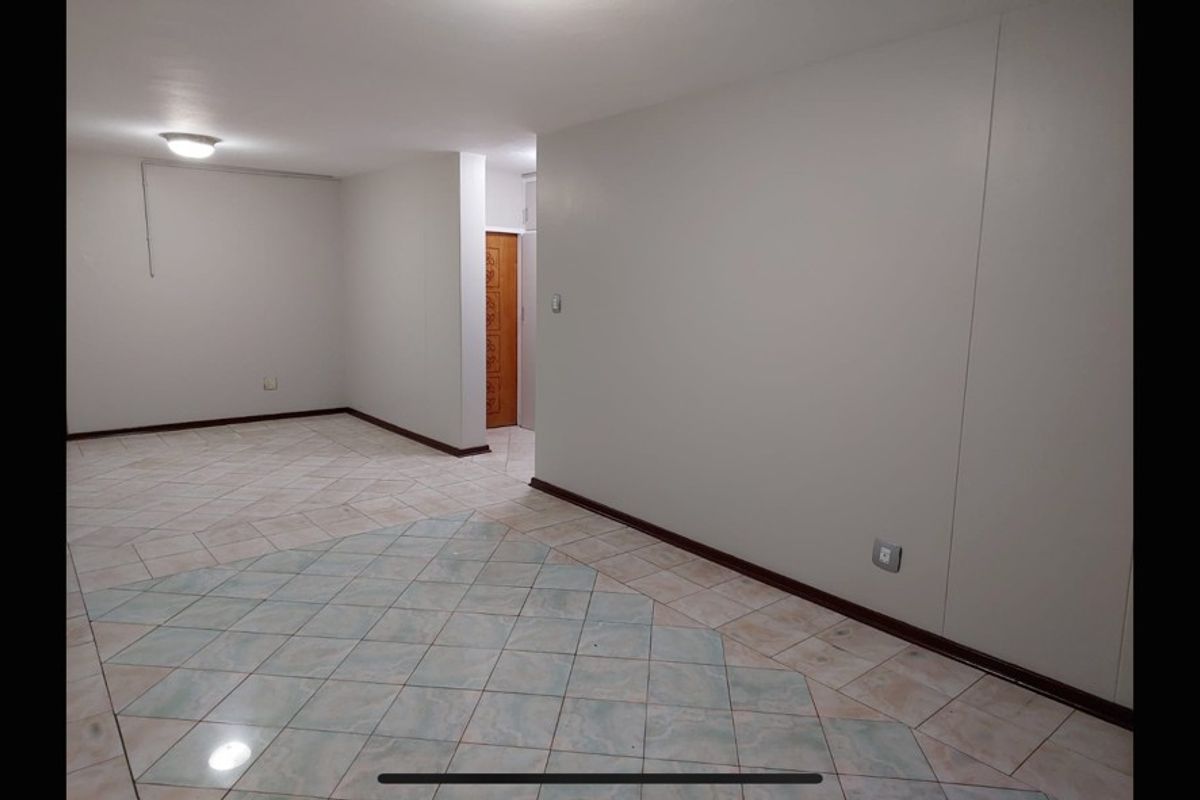 An empty, open-plan living area featuring neutral walls, tiled flooring, and basic lighting fixtures, providing a blank canvas for interior design.