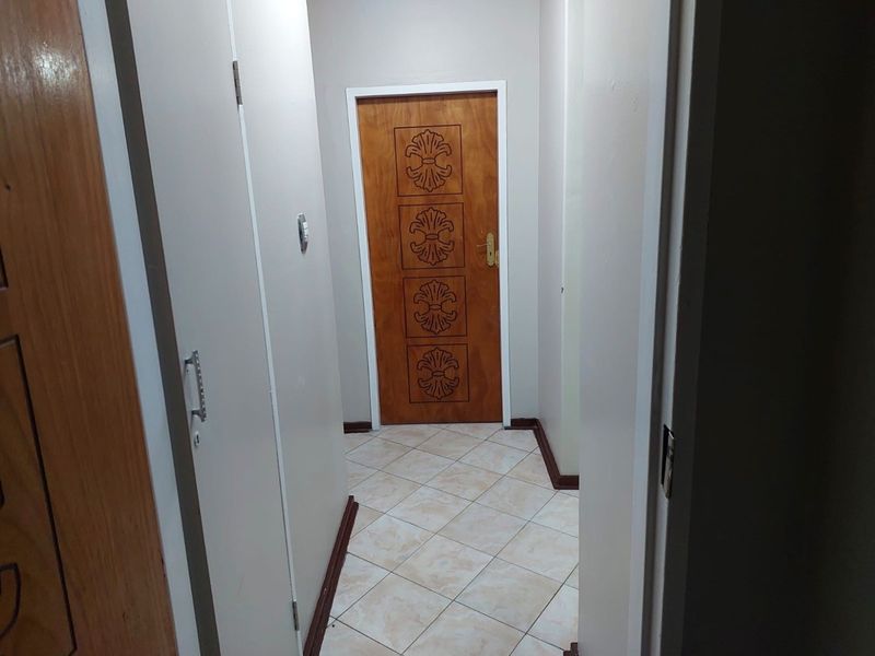 A clean, functional hallway featuring tiled flooring and wooden internal doors, providing access to various rooms within the apartment.