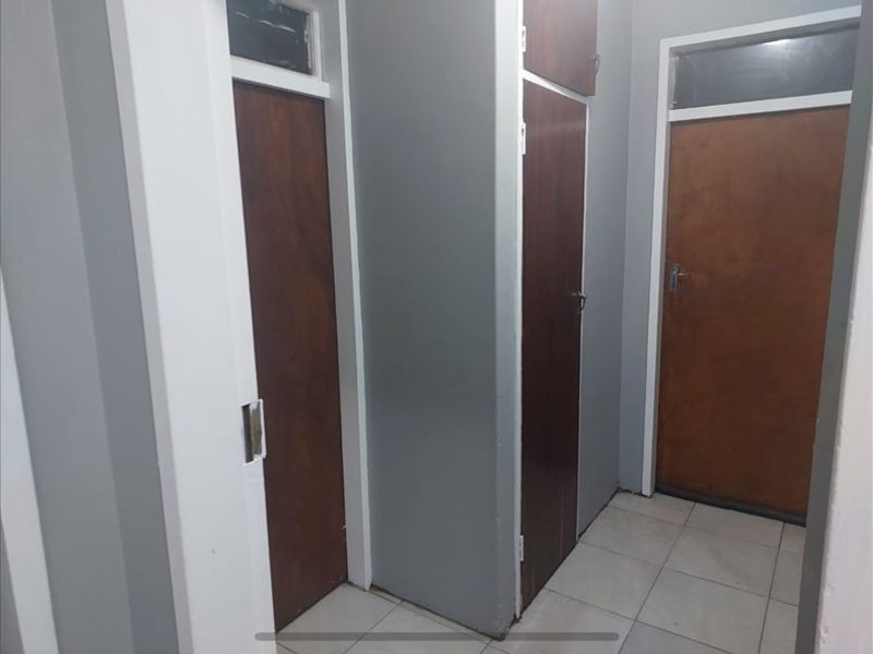 A functional hallway featuring tiled flooring and multiple built-in wooden doors with transom windows above.