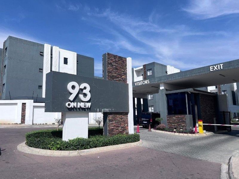 The entrance to 93 On New apartment complex, featuring a modern security gatehouse, boom gate access, and contemporary stone-clad signage.