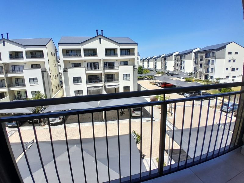 A view from a balcony overlooking the apartment complex parking area and surrounding residential buildings.