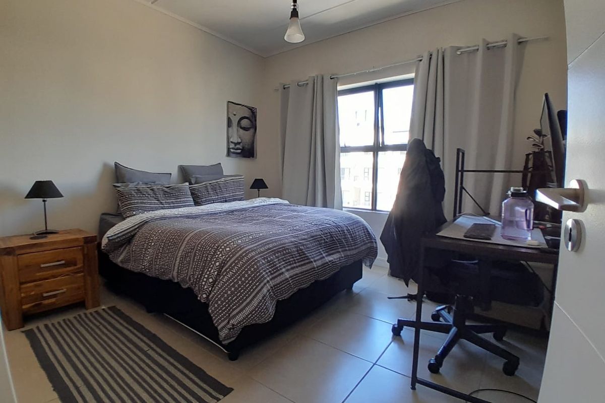 A functional bedroom featuring tiled flooring, a window with curtains, and a central pendant light fixture.