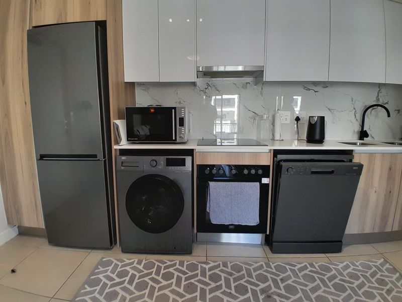 Modern kitchen featuring sleek white cabinetry, marble-look splashback, integrated appliances, and a functional layout with ample counter space.