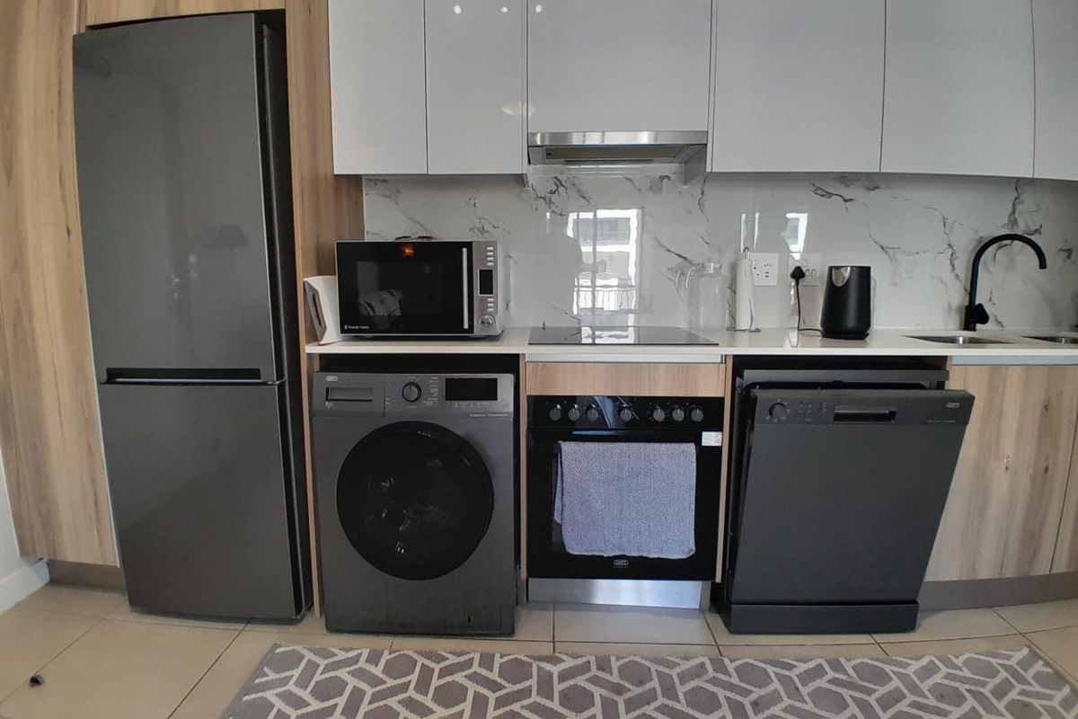 Modern kitchen featuring sleek white cabinetry, marble-look splashback, integrated appliances, and a functional layout with ample counter space.