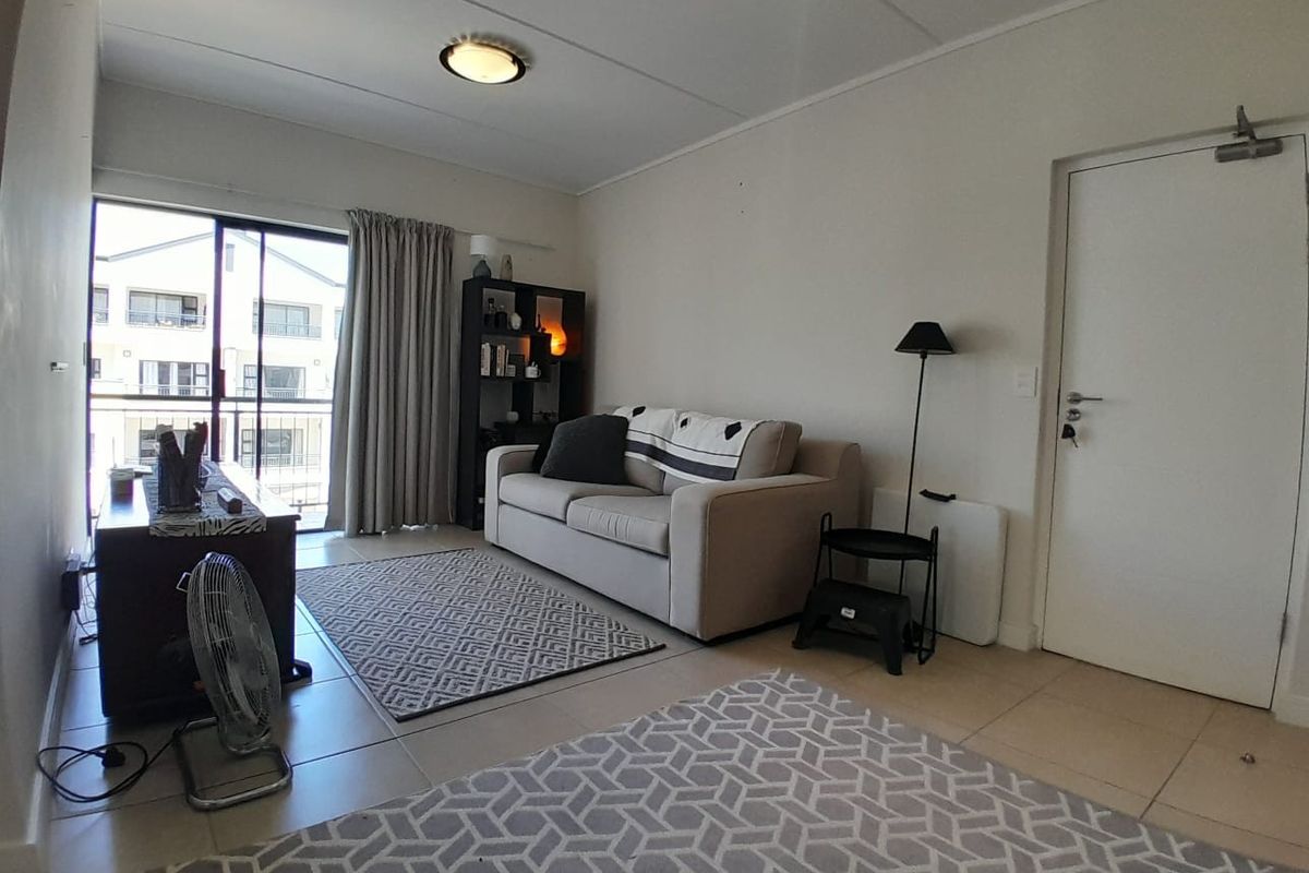 A living room featuring tiled flooring and a sliding glass door leading to a balcony, providing natural light to the space.