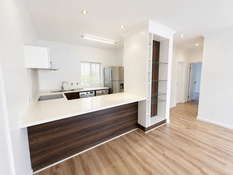 Modern, clean-lined kitchen featuring quartz countertops, dark wood-grain cabinetry, integrated shelving, and high-quality laminate flooring in an open-plan layout.