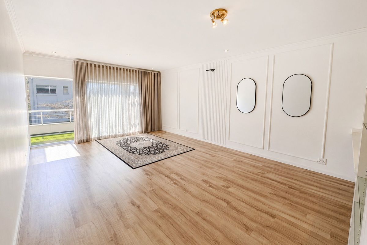 Bright and spacious living area featuring modern laminate flooring, elegant wainscoting, slatted wall detailing, and direct access to a private balcony.