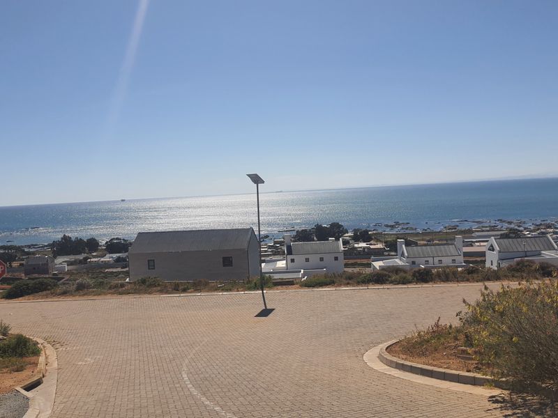 A scenic elevated view overlooking the coastal landscape, featuring a paved road and nearby residential properties with ocean views.