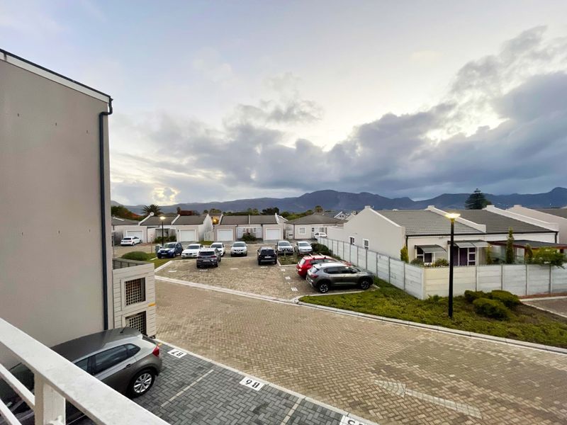 Elevated view overlooking a residential complex parking area with paved driveways and mountain views in the background.