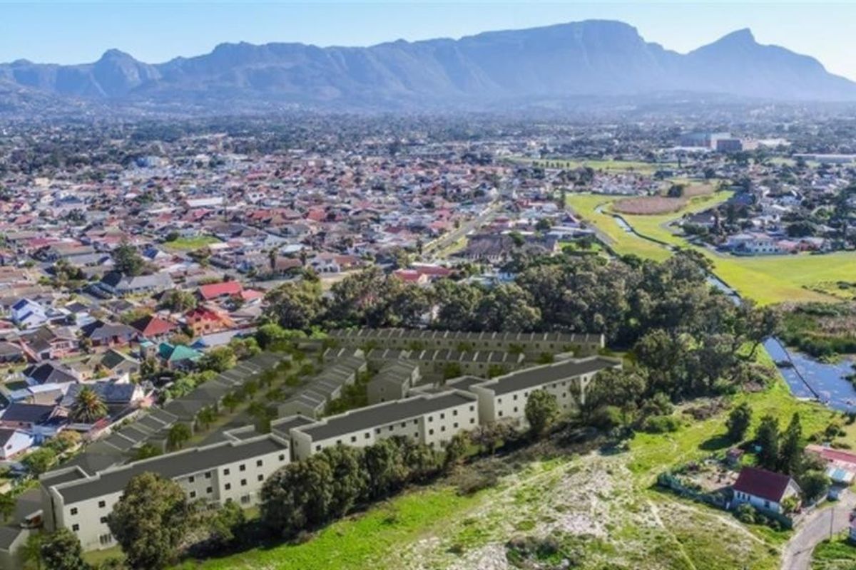 An aerial view of a residential apartment complex development situated in a suburban area with mountain views.