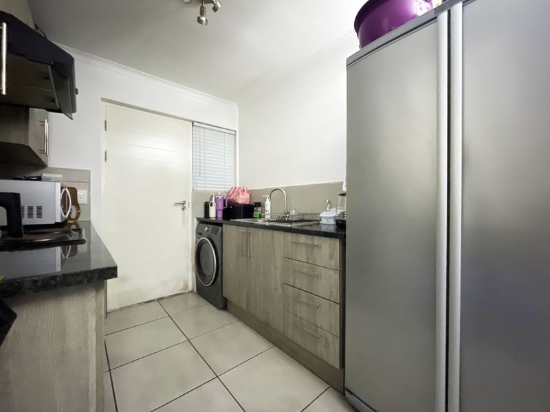 A functional kitchen featuring granite countertops, built-in cabinetry, tiled flooring, and an integrated extractor fan, providing a practical workspace.