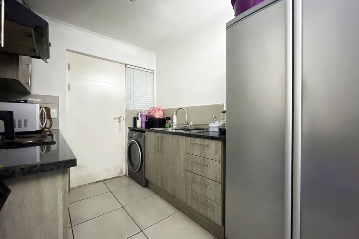 A functional kitchen featuring granite countertops, built-in cabinetry, tiled flooring, and an integrated extractor fan, providing a practical workspace.