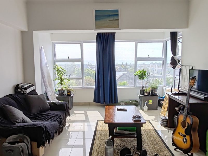 Open-plan living area featuring tiled flooring and large windows that provide ample natural light and views of the surrounding neighbourhood.
