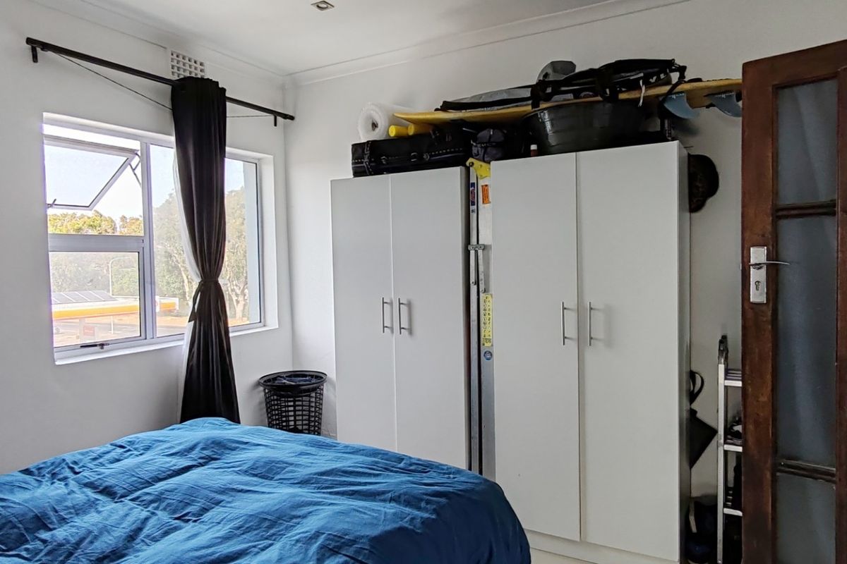 Bedroom featuring built-in cupboards, a large window providing natural light, and a classic timber-framed glass door.