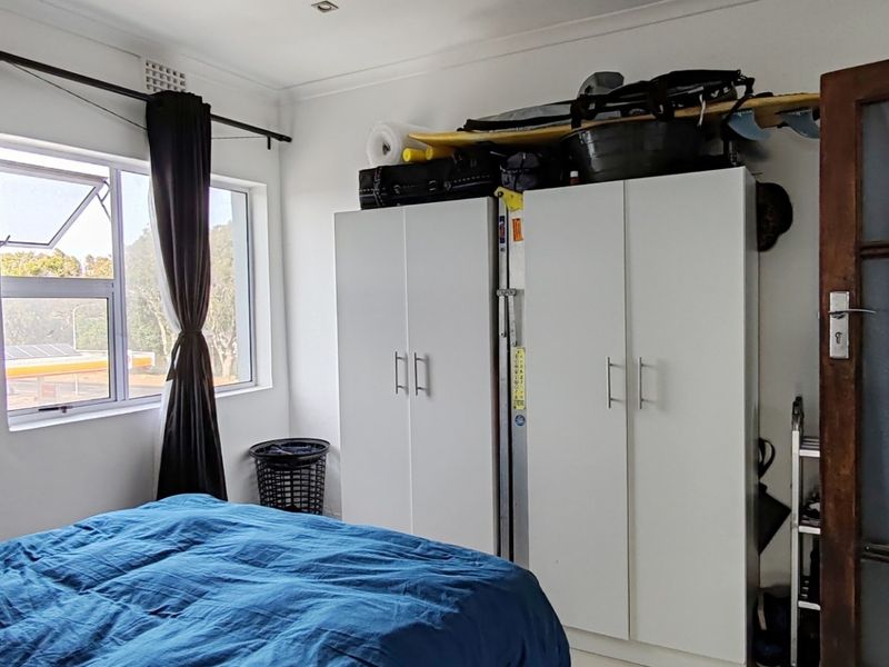 Bedroom featuring built-in cupboards, a large window providing natural light, and a classic timber-framed glass door.