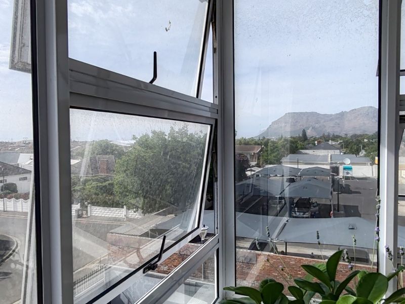 A view from an apartment window overlooking the surrounding neighbourhood and distant mountains.