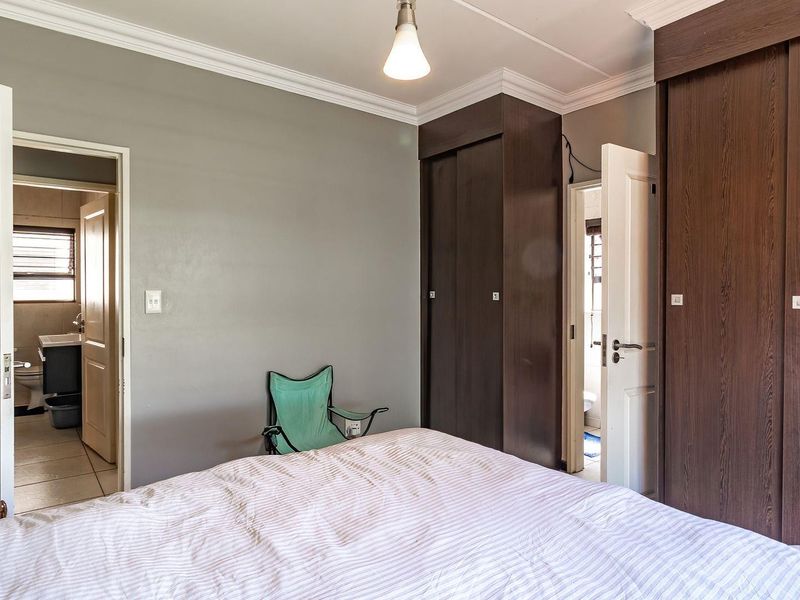 A bedroom featuring built-in dark wood cupboards, crown molding, and direct access to an en-suite bathroom.