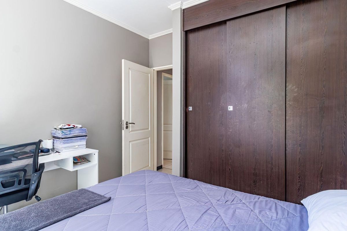 A well-maintained bedroom featuring a large built-in sliding door wardrobe, neutral wall finishes, and classic coving detail.