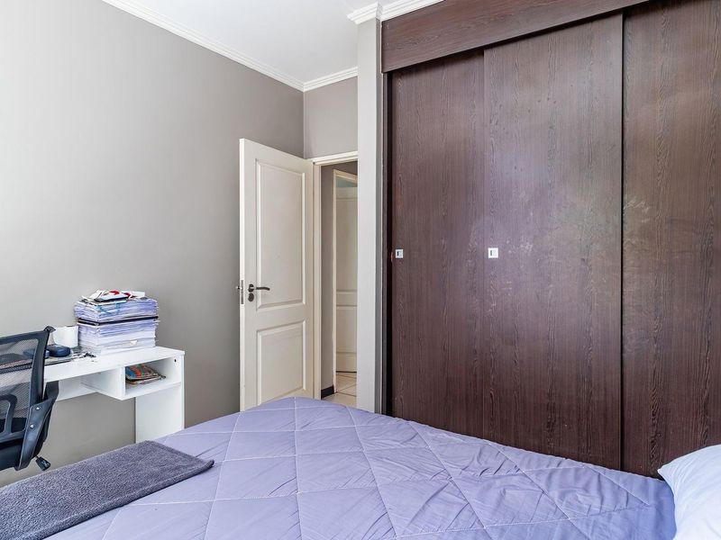 A well-maintained bedroom featuring a large built-in sliding door wardrobe, neutral wall finishes, and classic coving detail.