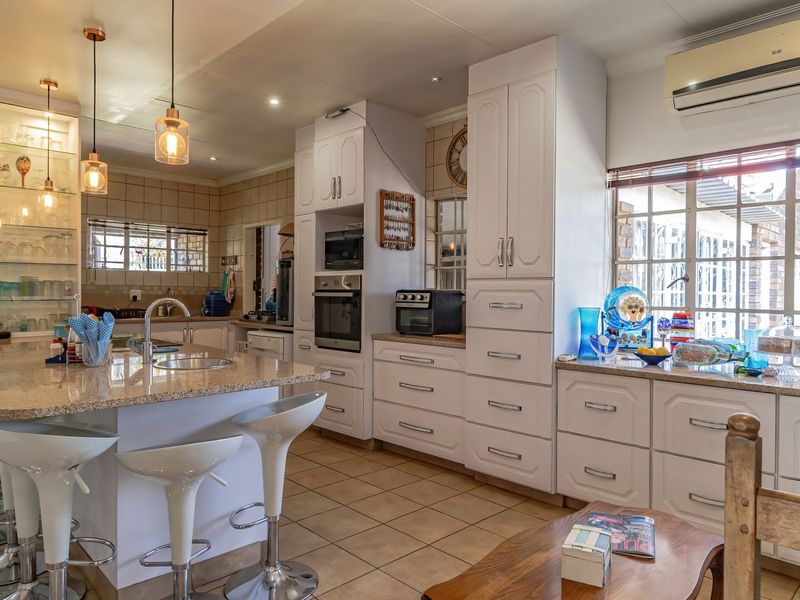 Spacious kitchen featuring a central island with granite countertops, built-in oven and microwave, ample cabinetry, and tiled flooring.