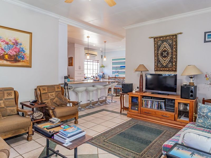 Open-plan living area featuring ceramic tile flooring, crown molding, and a kitchen breakfast bar with pendant lighting.