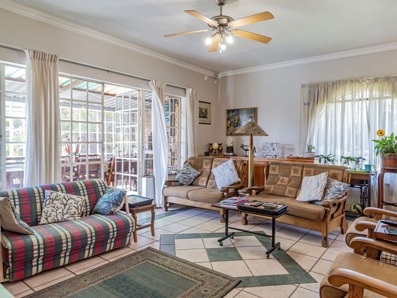 Spacious living room featuring tiled flooring, a ceiling fan, and large sliding glass doors providing access to the outdoor patio area.