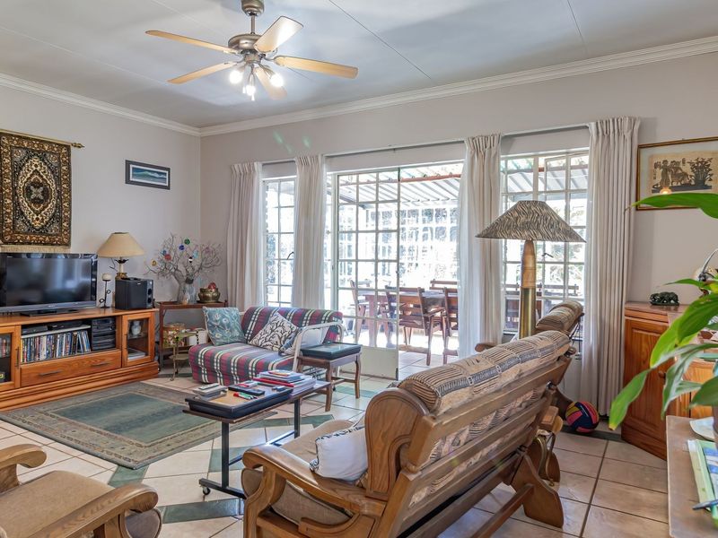 Spacious living room featuring tiled flooring, a ceiling fan, and large sliding glass doors that provide natural light and access to the patio.