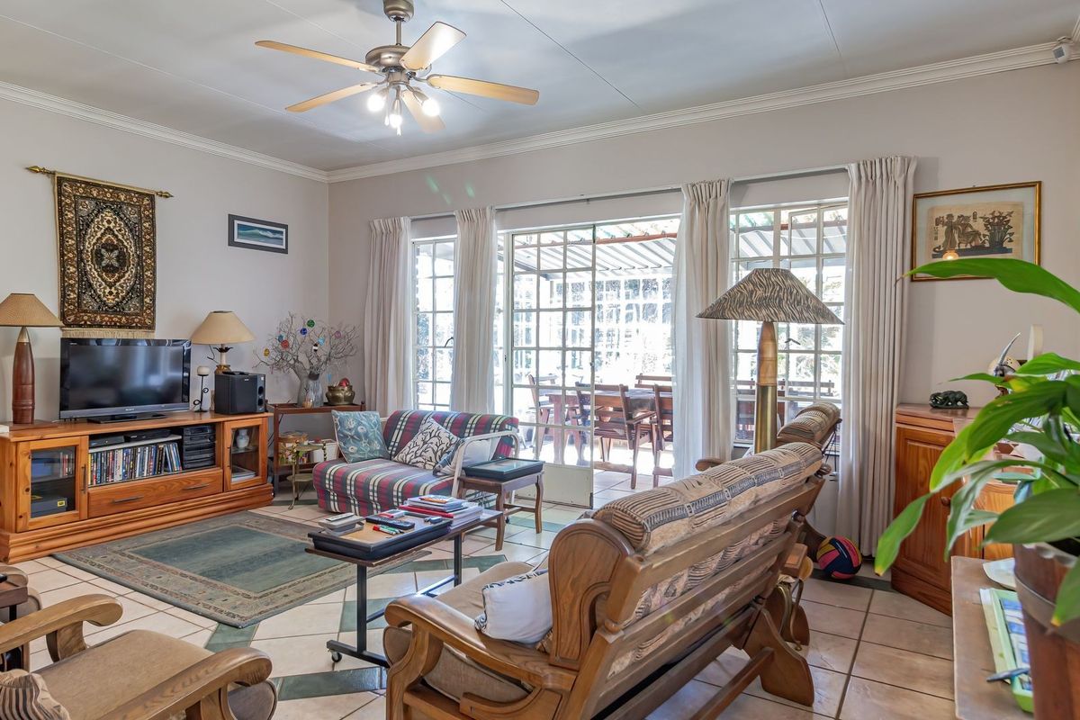 Spacious living room featuring tiled flooring, a ceiling fan, and large sliding glass doors that provide natural light and access to the patio.