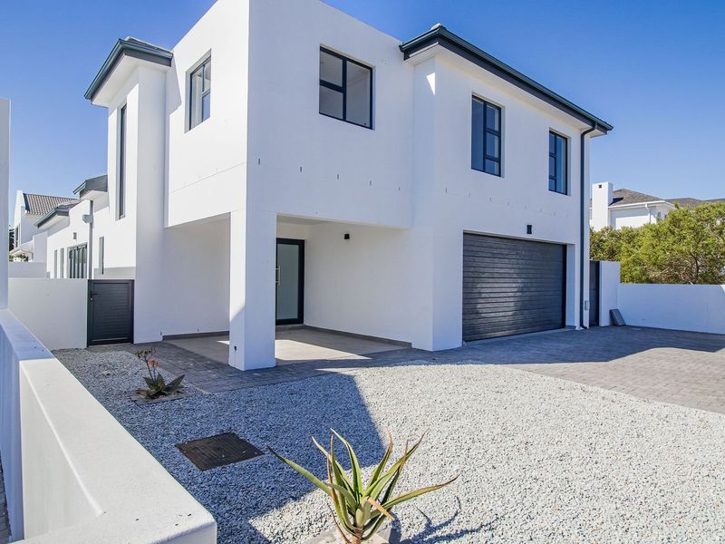 Modern double-story residential home featuring a clean white facade, paved driveway, double garage, and a low-maintenance gravel garden.
