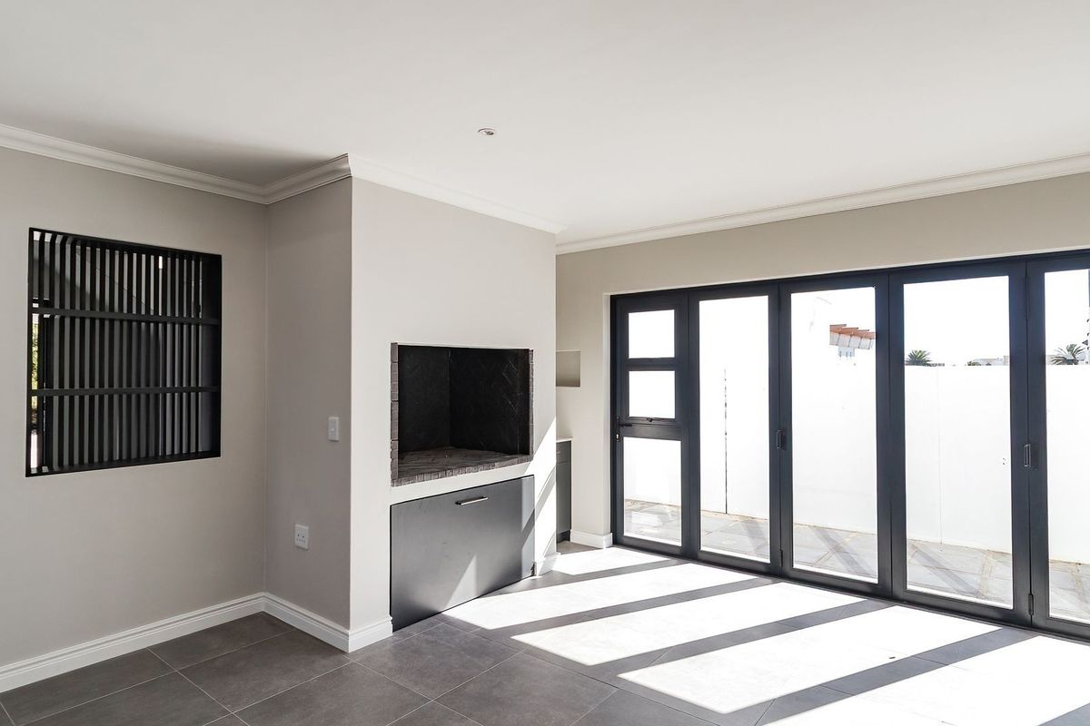 Bright and modern living area featuring a built-in fireplace, sleek tiled flooring, and large aluminium stacker doors opening to the exterior.
