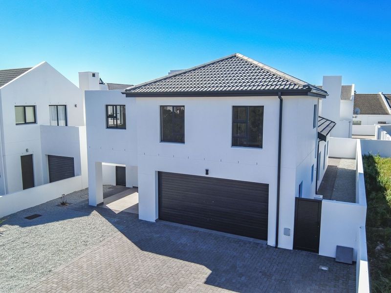 Modern two-story residential home featuring a clean white facade, tiled roof, paved driveway, and a secure double garage.