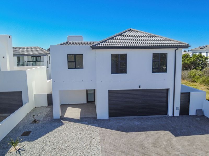 Modern two-story residential property featuring a clean white facade, dark tiled roof, double garage, and a paved driveway entrance.