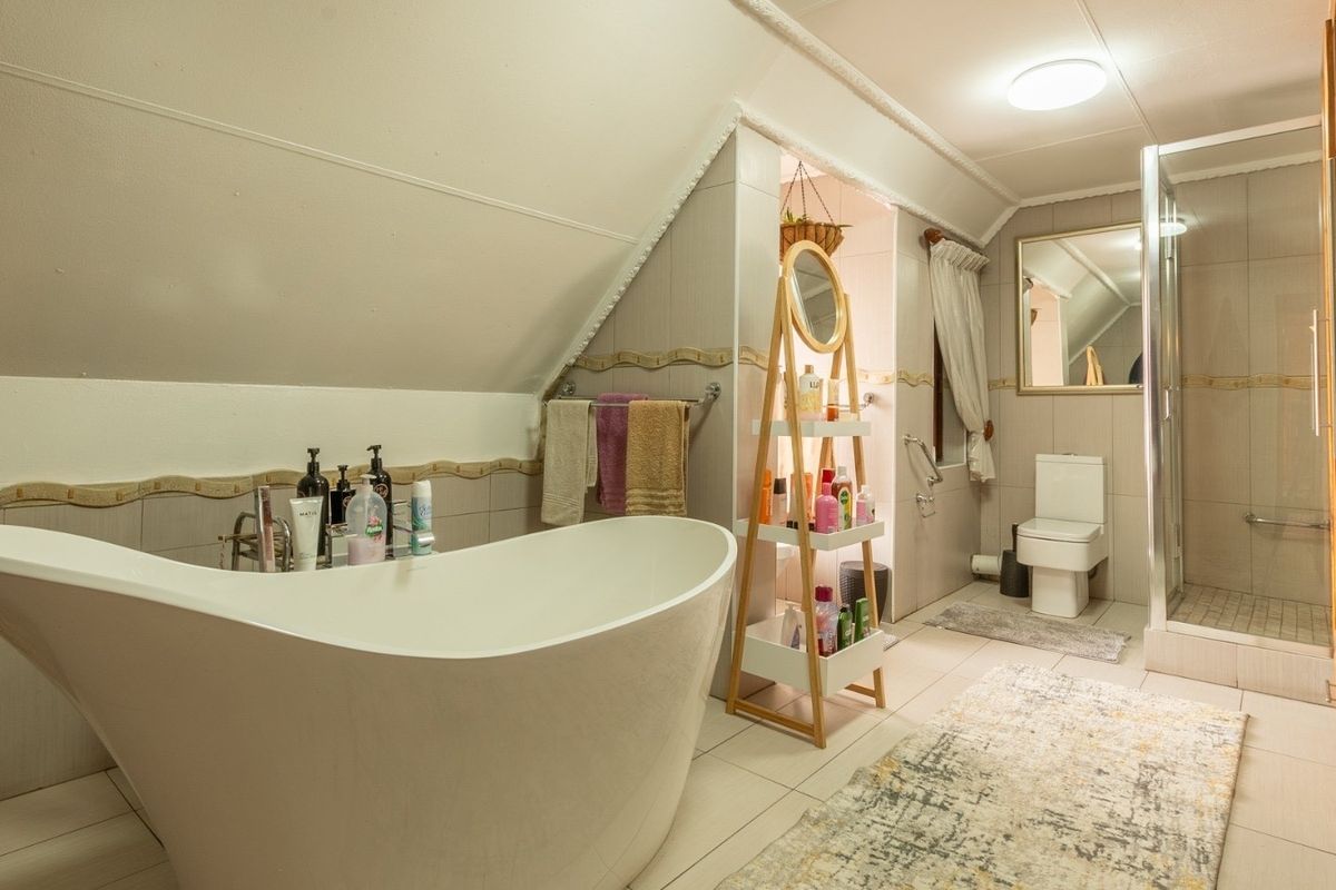 A well-appointed bathroom featuring a modern freestanding bathtub, a separate glass-enclosed shower, and a wall-mounted toilet with neutral tiled finishes.