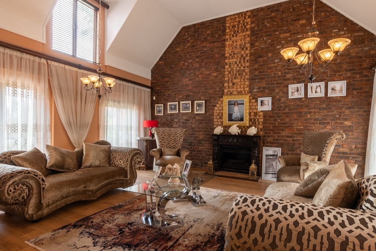 Spacious living room featuring a striking exposed brick wall, vaulted ceilings, and a built-in fireplace, creating a warm and inviting atmosphere.