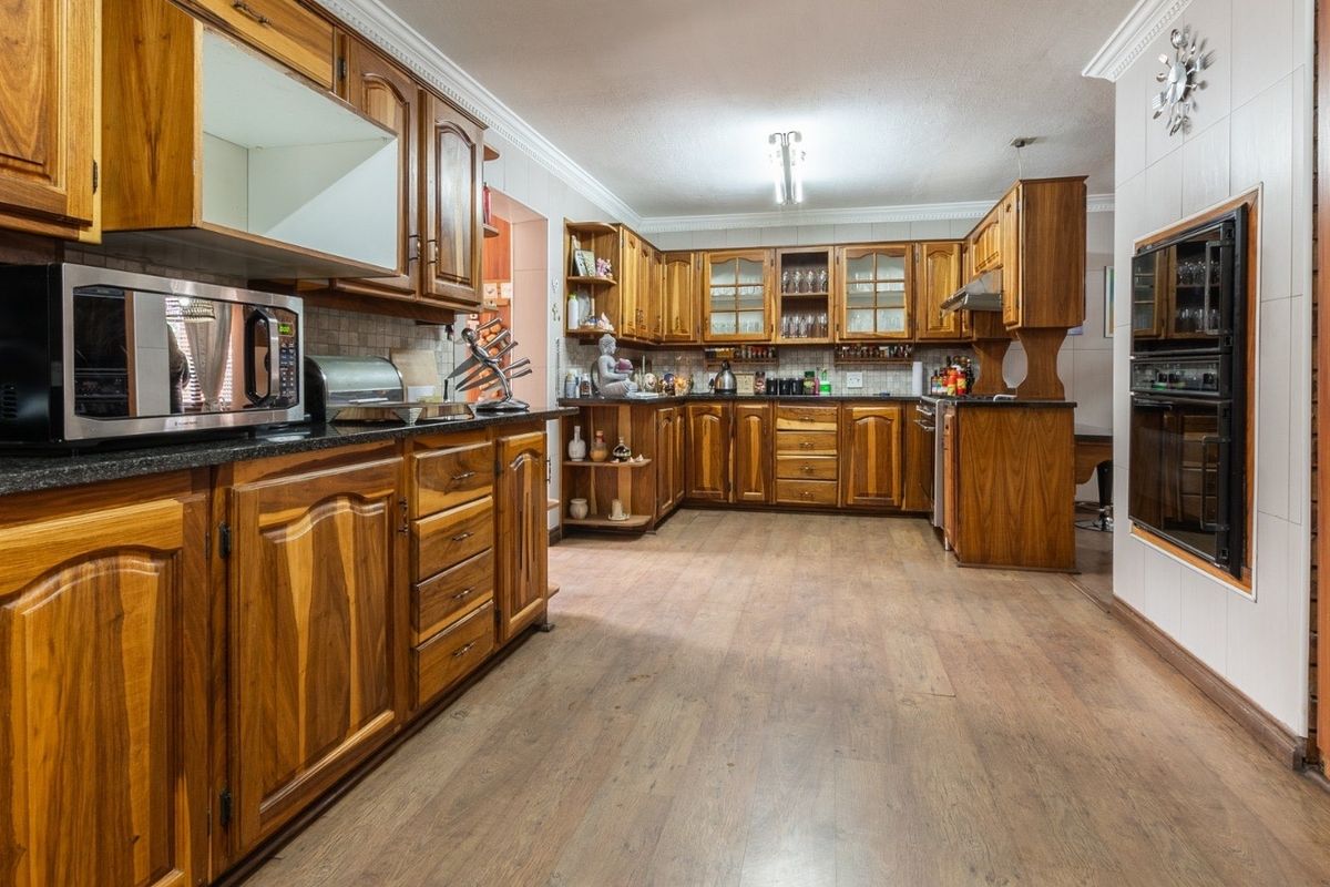 Spacious kitchen featuring extensive wooden cabinetry, granite countertops, and a built-in double oven, offering a traditional aesthetic with ample storage and workspace.