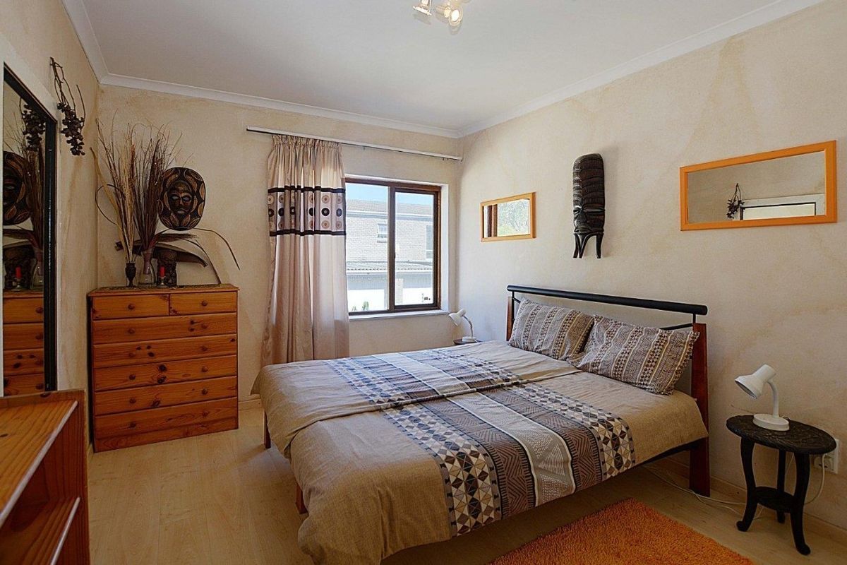 A standard bedroom featuring neutral wall finishes, a window with curtain track, and coving detail. Visible water staining on the wall requires attention.